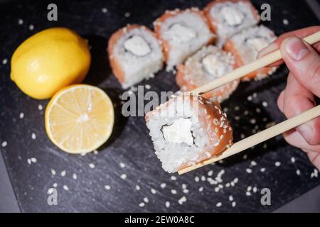 Sushi-Brötchen auf schwarzem Brett auf dunklem Hintergrund Stockfoto