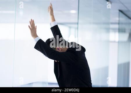 Der erschöpfte Geschäftsmann lehnte sich im Büro am Fenster Stockfoto
