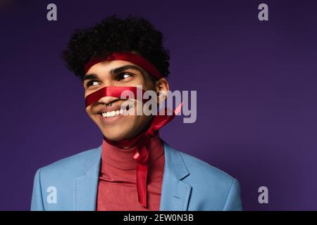 Positive afroamerikanische Mann mit rotem Band auf lila gebunden Stockfoto