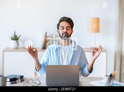 Funktionierendes Zen. Ruhiger Östlicher Geschäftsmann Meditiert Am Arbeitsplatz Im Büro Stockfoto