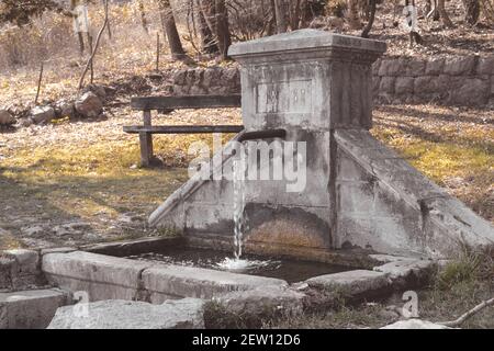 Das Wasser, das aus dem Wasserhahn des steinernen Wassers fließt Quelle im Park Stockfoto