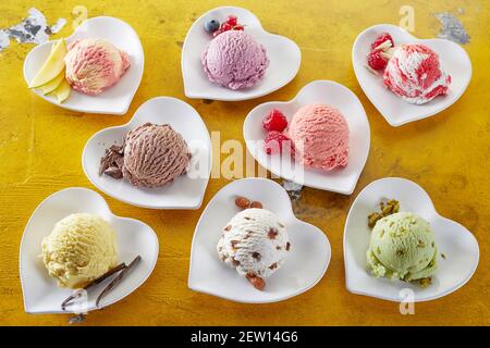 Von oben köstliche Kugeln Gelati mit reifen Beeren Und Mangoscheiben mit Pistazien auf herzförmigen Tellern Stockfoto