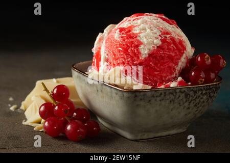 Closeup Schüssel mit leckeren Vanille-Eis mit Beere gekrönt Sirup und dekoriert mit roten Johannisbeeren berried und weißer Schokolade Balken Stockfoto