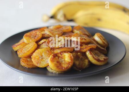 Karamellisierte Kochbananen. Ein traditioneller Tee-Snack aus Kerala. Reife Kochbanane in Scheiben schneiden und in einer Pfanne mit etwas braunem Sug anrösten Stockfoto