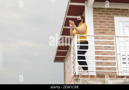 Kolumbianische Frau applaudiert von ihrem Balkon aus in Dankbarkeit an die Medizinisches Personal Stockfoto