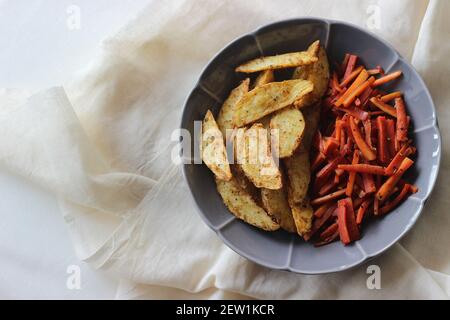 Sautierte Karotten und luftgebratene Kartoffelkeile. Der einfachste und gesunde Weg, um Karotten. Aufnahme auf weißem Hintergrund Stockfoto