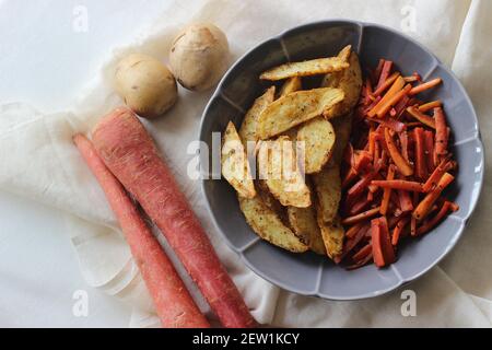 Sautierte Karotten und luftgebratene Kartoffelkeile. Der einfachste und gesunde Weg, um Karotten. Aufnahme auf weißem Hintergrund Stockfoto