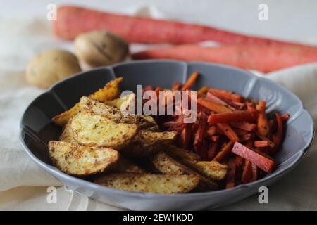 Sautierte Karotten und luftgebratene Kartoffelkeile. Der einfachste und gesunde Weg, um Karotten. Aufnahme auf weißem Hintergrund Stockfoto