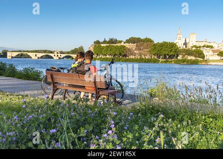 Frankreich, Vaucluse, Avignon, ViaRhôna, ein junges Radlerpaar, das auf dem Chemin des Berges mit der Brücke Saint Benezet über die Rhône aus dem 12th. Jahrhundert posiert, die zum UNESCO-Weltkulturerbe gehört, und der Kathedrale von Doms aus dem 12th. Jahrhundert Stockfoto