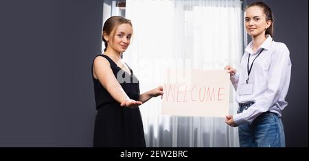 Junge Mode-Shop-Besitzer in ihrer Boutique stehen, stolz begrüßen den Kunden. Stockfoto