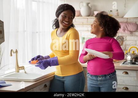 Helfende Hand. Niedlich Wenig Schwarz Mädchen Hilft Sie Mutter In Küche Stockfoto