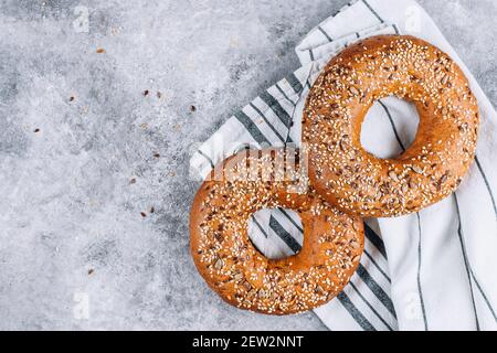Gesunder Bio-Vollkorn-Bagel auf Beton-Hintergrund-Tisch. Frühstücksbrot. Platz kopieren, Draufsicht Stockfoto
