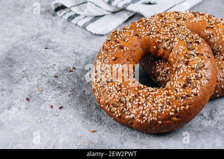 Gesunder Bio-Vollkorn-Bagel auf Beton-Hintergrund-Tisch. Frühstücksbrot. Platz kopieren, Draufsicht Stockfoto
