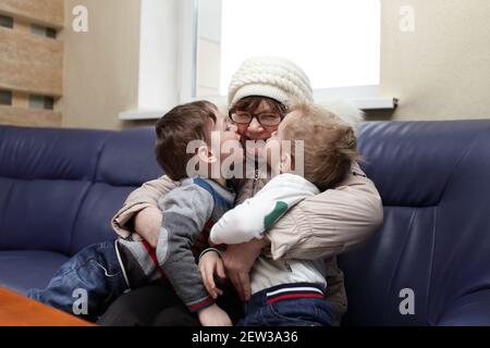 Enkel küssen ihre Großmutter auf dem Sofa Stockfoto