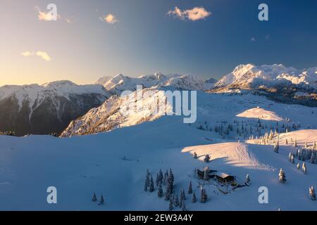 Luftaufnahme der Winterlandschaft mit schneebedecktem Wald in den Bergen mit schönem Sonnenuntergangslicht. Stockfoto