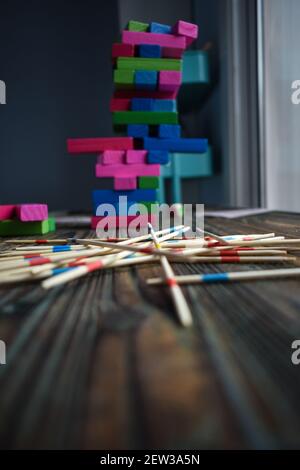 Eine vertikale Aufnahme von bunten Jenga Spielblöcken auf gestapelt Einander im Vordergrund von Holzstäben Stockfoto