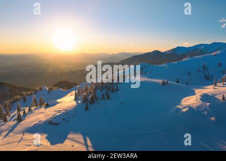 Luftaufnahme der Winterlandschaft Wald mit schönen Sonnenuntergang in der Ferne. Stockfoto