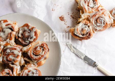 Teller mit frisch gebackenen Zimtschnecken mit Zuckerguss bedeckt. Stockfoto