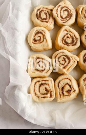 Backform gefüllt mit 12 Scheiben roher Zimtschnecken Teig fertig zum Backen. Stockfoto