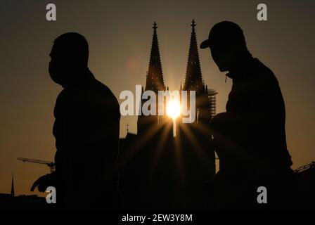 Köln, Deutschland. März 2021, 02nd. Männer in Masken gehen in der Abendsonne an der Kathedrale vorbei. Am Mittwoch (03,03.2021) werden Bund und Länder darüber diskutieren, wie die Maßnahmen gegen die Corona-Pandemie weitergehen sollen. Quelle: Oliver Berg/dpa/Alamy Live News Stockfoto