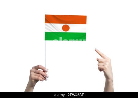 Eine schöne weibliche Hand hält eine Niger-Flagge, auf der sie den Finger ihrer anderen Hand zeigt, isoliert auf weißem Hintergrund. Stockfoto