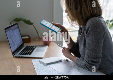 Designerin mit Smartphone, macht eine Pause von der Arbeit und hört im Clubhaus Lautsprecher Stockfoto