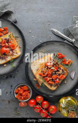 Vorspeise serviert mit gegrilltem Brot, Tomaten, Zwiebeln und Kräutern. Bruschetta mit gerösteten Tomaten. Kontinentales leckeres gesundes Frühstück Stockfoto