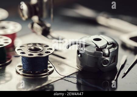 Arbeitsteil der antiken Nähmaschine. Selektiver Fokus auf Garnspule, Metall-Shuttle und Nähnadeln. Stockfoto