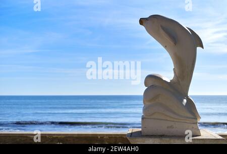 Delfinstatue auf blauem Himmel Hintergrund während sonnigen Tages in touristischen spanischen Stadt Santa Pola. Provinz Alicante, Costa Blanca, Spanien Stockfoto