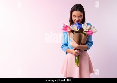 Studio Schuss von gut aussehende Frau riecht Tulpe Blumen, genießt angenehmen Geruch, stilvolle Kleidung innen. Schöne kaukasische Dame halten schöne Bouquet von Stockfoto