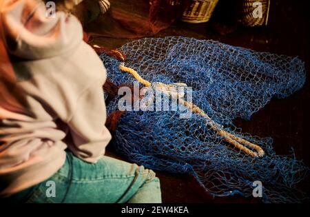 Junge Frau repariert ein Fischernetz Stockfoto