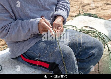 Hände des Fischers, die ein Netz mit einem Messer reparieren Stockfoto