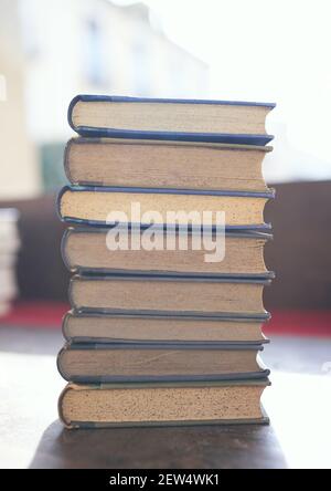 Mehrere alte und leicht abgenutzte Bücher in einem Turm gestapelt Auf einem Schreibtisch Stockfoto