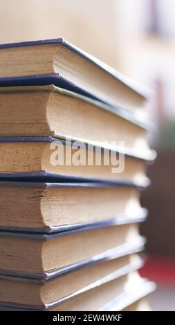 Mehrere alte und leicht abgenutzte Bücher in einem Turm gestapelt Auf einem Schreibtisch Stockfoto