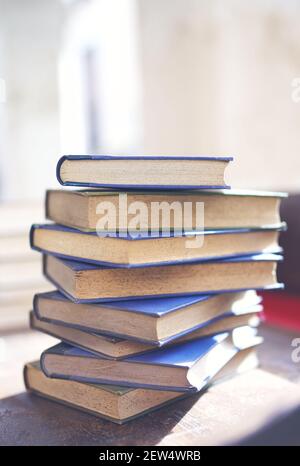 Mehrere alte und leicht abgenutzte Bücher in einem Turm gestapelt Auf einem Schreibtisch Stockfoto