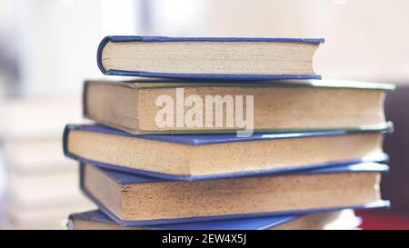 Mehrere alte und leicht abgenutzte Bücher in einem Turm gestapelt Auf einem Schreibtisch Stockfoto