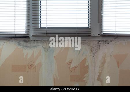 Wasserflecken an der Wand unter dem Kunststofffenster. Vorbereitung für die Renovierung der Wohnung. Stockfoto