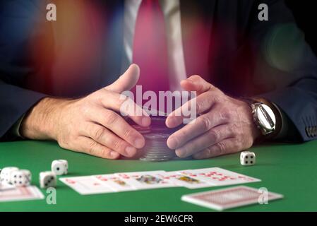 Geschäftsmann am grünen Spieltisch mit Spielchips, Karten und Würfeln, die Poker und Blackjack im Casino spielen Stockfoto