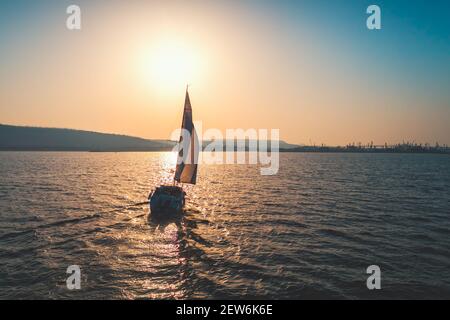 Segelschiff Yacht mit weißen Segeln auf geöffnetem Meer. Luftaufnahme - Drohne Blick auf Segelboot in windigem Zustand. Stockfoto