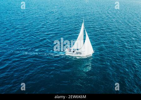 Segelschiff Yacht mit weißen Segeln auf geöffnetem Meer. Luftaufnahme - Drohne Blick auf Segelboot in windigem Zustand. Stockfoto