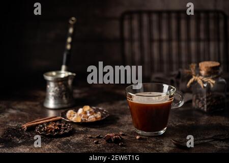 Kaffee in einem Glas mit Zucker und Kaffeebohnen auf Dunkler Hintergrund Stockfoto