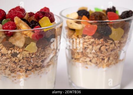 Müsli Dessert mit Joghurt und kandierten oder getrockneten Früchten mit Himbeeren auf der Oberseite in Glas isoliert auf weißem Hintergrund. Frühstück Müsli Stockfoto