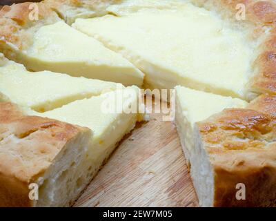 Nahaufnahme von dreieckigen Scheiben Sauerrahm Pie - ein nationales tatarisches Gericht. Ein riesiger selbstgemachter Käsekuchen mit gerösteten Rändern und zarter Füllung auf einem Holz Stockfoto