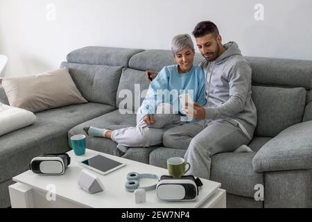 Schöne junge liebevolle Paar Bindung zueinander und machen Selfie beim gemeinsamen Sitzen auf der Couch Stockfoto