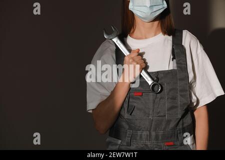 Portrait weibliche Arbeiter tragen Schutzmaske Gesicht, Schutzhelm und Anzug und mit großen Schraubenschlüssel, Schlüssel in den Händen. Für die industrielle Arbeit durch Kov Stockfoto