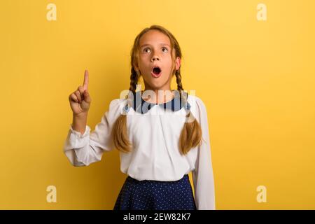 Der junge Student ist schockiert und zeigt etwas an. Gelber Hintergrund Stockfoto