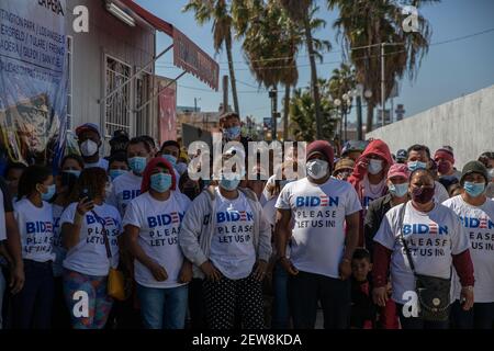 San Ysidro, Mexiko. März 2021, 02nd. "Biden, bitte lasst uns ein", liest sich auf Englisch auf den T-Shirts einer Gruppe von Migranten aus verschiedenen Hintergründen, die sich auf den Weg zum internationalen Grenzübergang "El Chaparral" gemacht haben. Die Migranten baten die neue US-Regierung um Asyl. Agenten der US-Grenzschutzbehörde (CPB) führten am Grenzübergang eine schwerere Operation durch, um einen Ansturm zu verhindern. Kredit: Stringer/dpa/Alamy Live Nachrichten Stockfoto