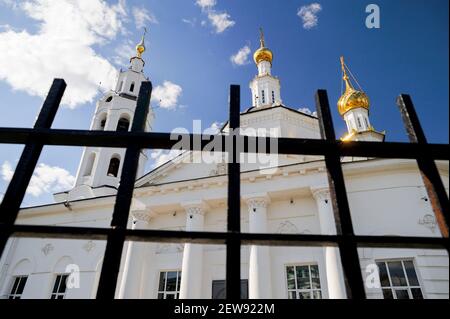 Weiße orthodoxe Kirche hinter schwarzem Metallzaun Stadtbild Stockfoto