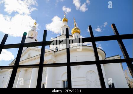 Weiße orthodoxe Kirche hinter schwarzem Metallzaun Stadtbild Stockfoto