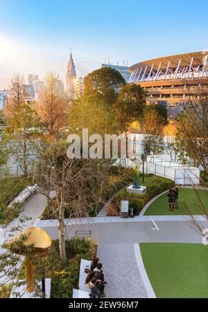 tokio, japan - 8 2021. februar: Sonnenuntergang auf dem Olympiastadion von Kasumigaoka vor dem japanischen sportolympiaplatz mit dem NTT Docomo Stockfoto